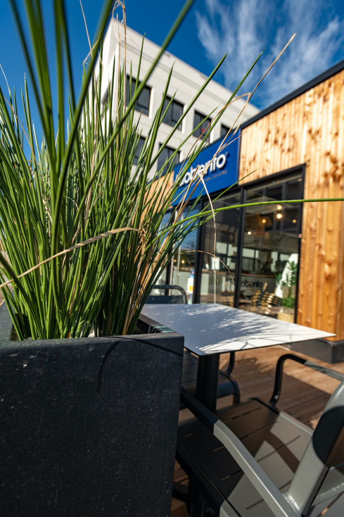 Vac de graminées créant des zones d'ombres sur la terrasse d'un restaurant